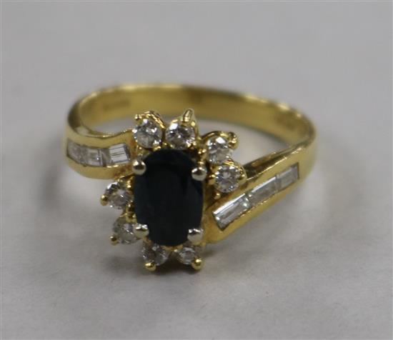 A modern 18ct gold, sapphire and diamond cluster ring with baguette cut diamond set shoulders, size O.